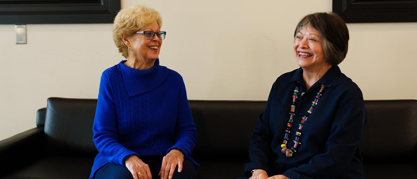 Two women sitting on couch talking