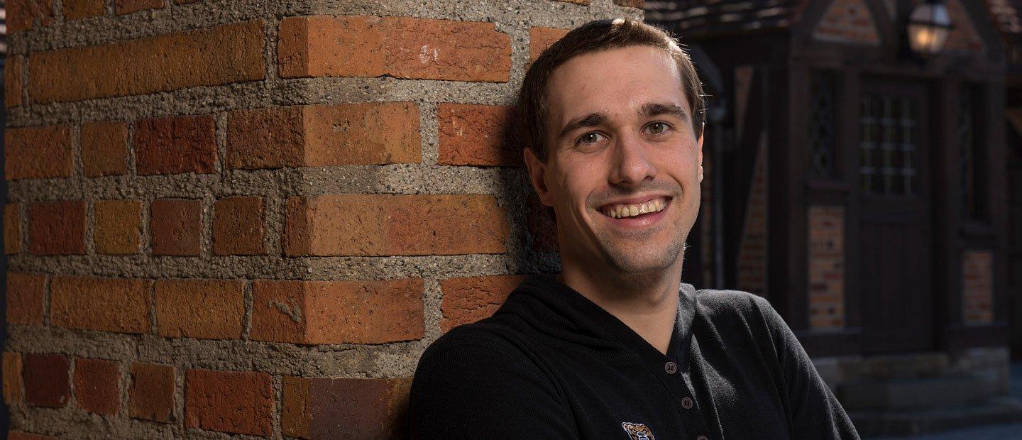 man in a black shirt leaning on a brick wall