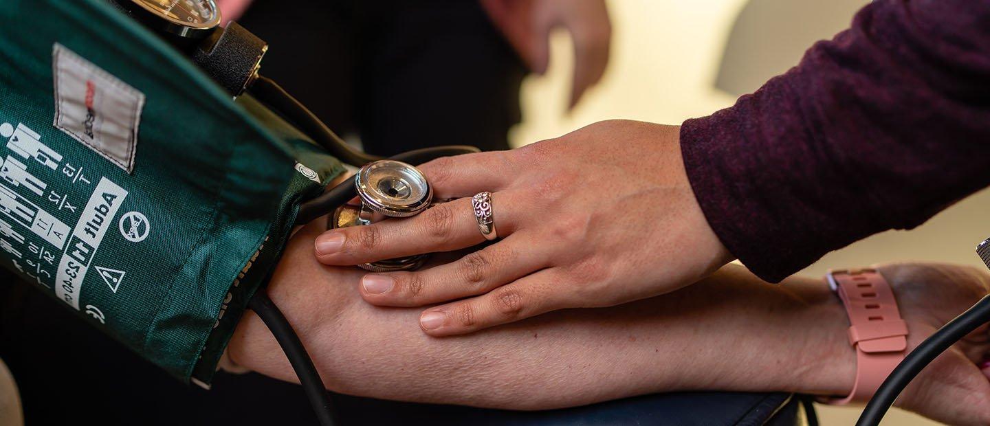 person taking someone's blood pressure using a green cuff