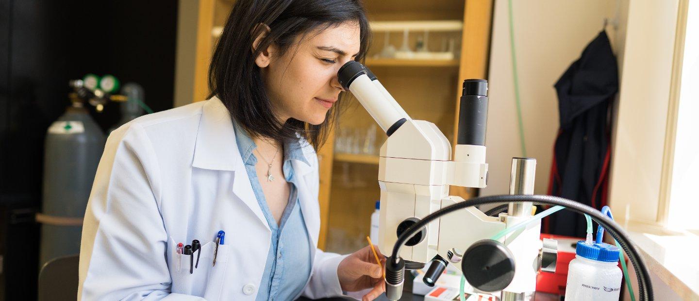 A woman looking into a microscope in a lab.